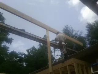 Carpenter setting a ridge beam over a new addition frame — Ice Dam Removal by Roofing Brothers in Castroville