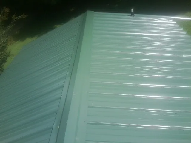 New green metal panels meeting at the ridge of a roof — Flat Roof Repair work by our crew in Castroville