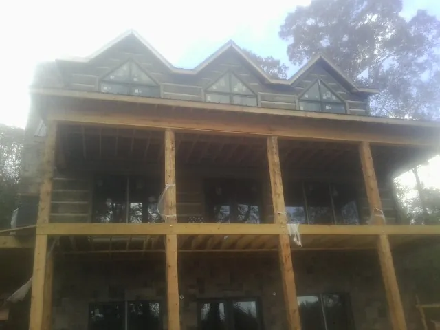 Dormers and porch framing on a large log home under construction — Roof Coating work by our crew in Castroville