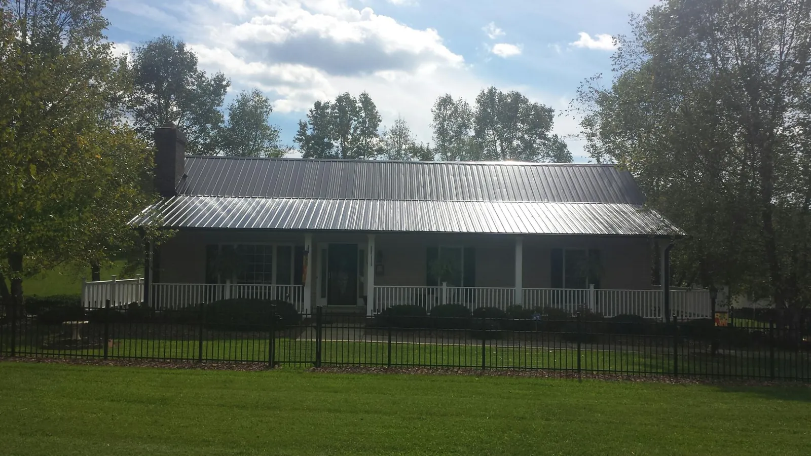 Gray metal roof on a brick ranch with a full width front porch — Gutter Guard Installation work by our crew in Castroville