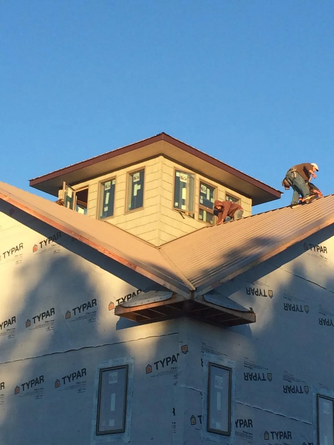 Roofers working around a rooftop cupola on a new metal roof at sunset — Roof Waterproofing in Castroville by Roofing Brothers
